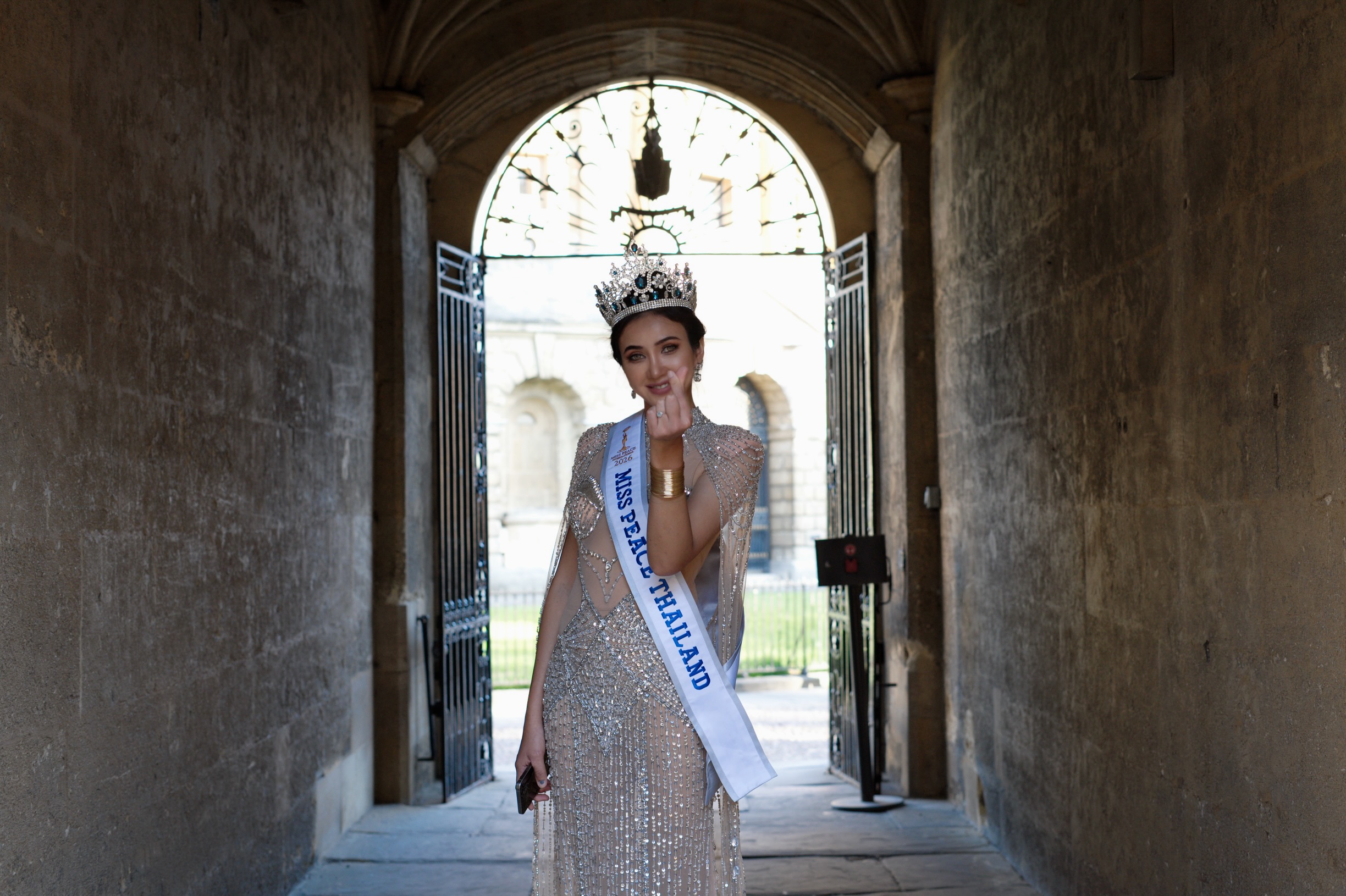 A golden trophy featuring two hands shaking, displayed on a shelf with a framed picture and a light.